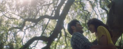 a man and a woman standing in front of a tree