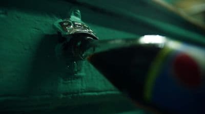 a close up of a metal object on a green wall
