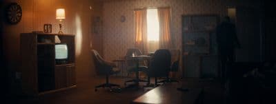 a dark room with a table and chairs and a tv