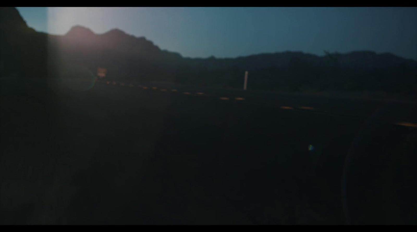 a blurry photo of a road with mountains in the background