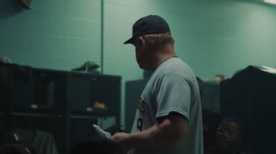 a man in a baseball uniform standing in a locker room