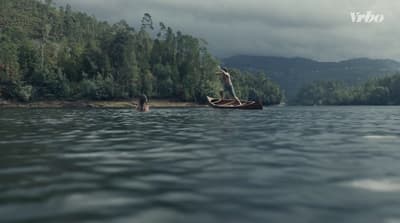 a man standing on a boat in the middle of a lake