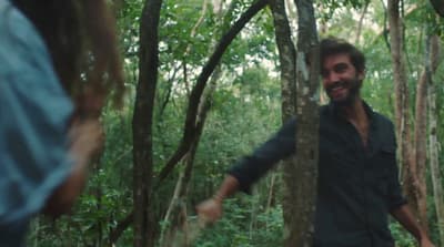 a man and a woman walking through a forest