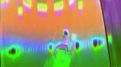 a blurry image of a bottle in front of a colorful wall