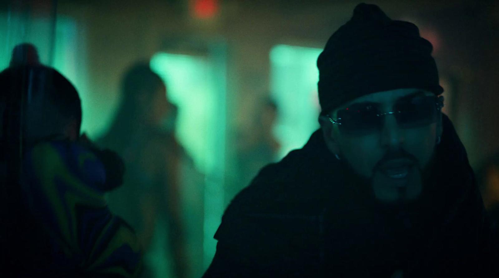 a man wearing sunglasses and a beanie in a dark room