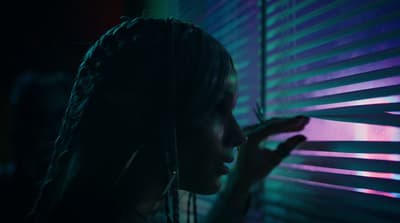 a woman standing next to a window covered in blinds