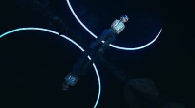 a man standing on top of a wooden pole in the dark