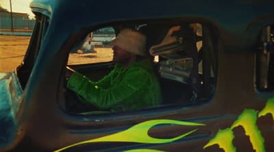 a man in a green jacket driving a truck