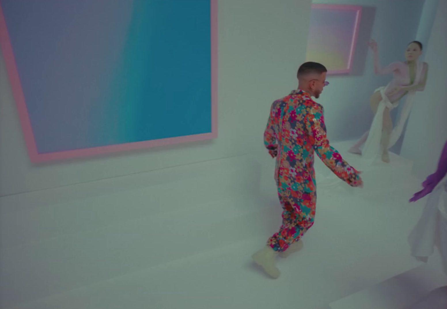 a man in a colorful suit standing in front of a painting