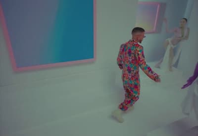 a man in a colorful suit standing in front of a painting