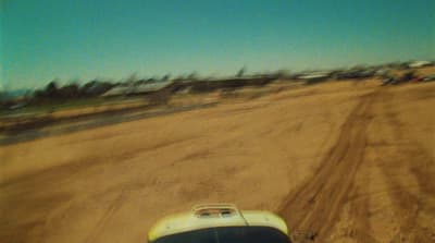 a car driving down a dirt road next to a forest