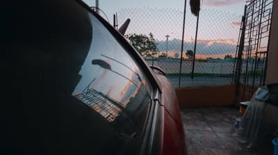 a red car parked next to a tall fence