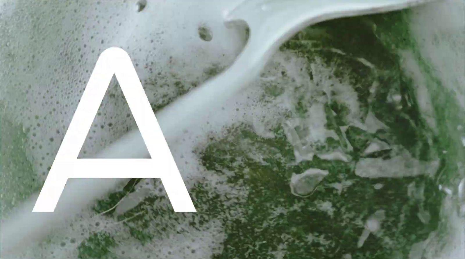 a white letter sitting on top of a green liquid