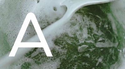 a white letter sitting on top of a green liquid