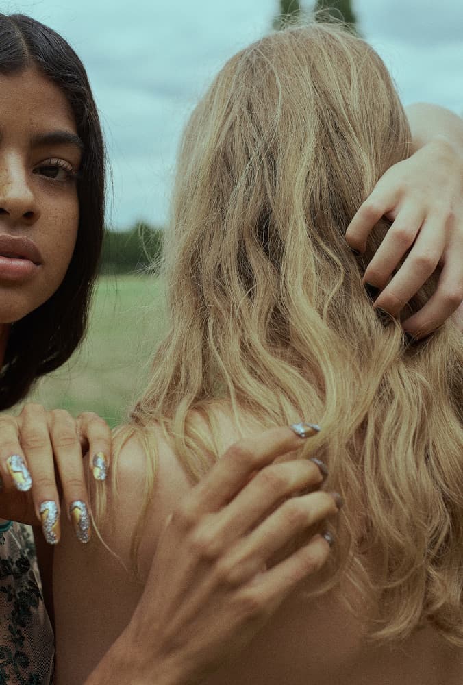 two women standing next to each other in a field