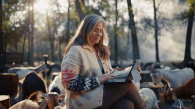 a woman sitting on a bench in front of a herd of cows
