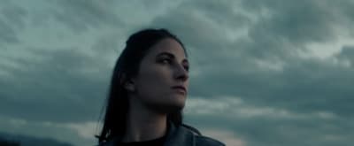 a woman standing in front of a cloudy sky