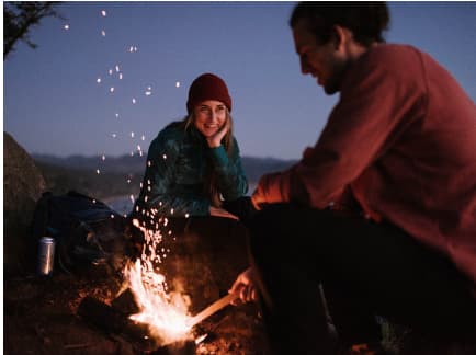 a man and a woman sitting around a campfire