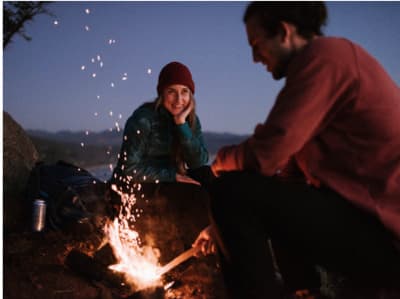 a man and a woman sitting around a campfire