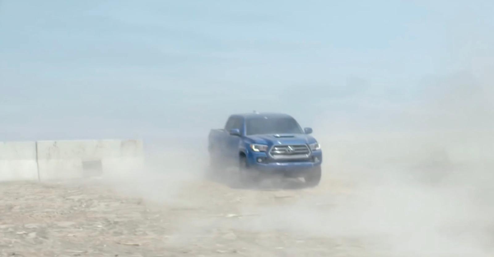 a blue truck driving down a dirt road