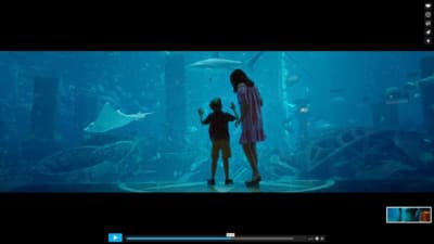 a woman and a child standing in front of a fish tank