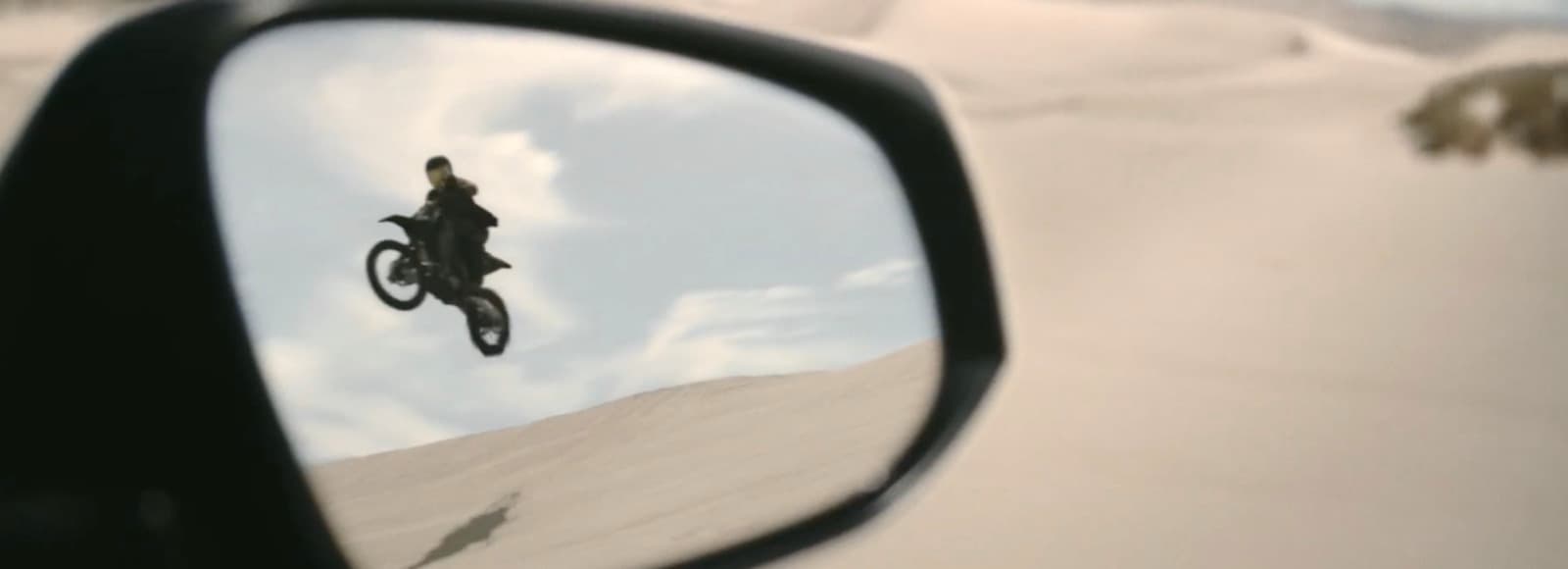 a rear view mirror with a person on a bike in the reflection