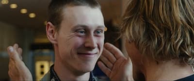 a man is smiling and touching his face