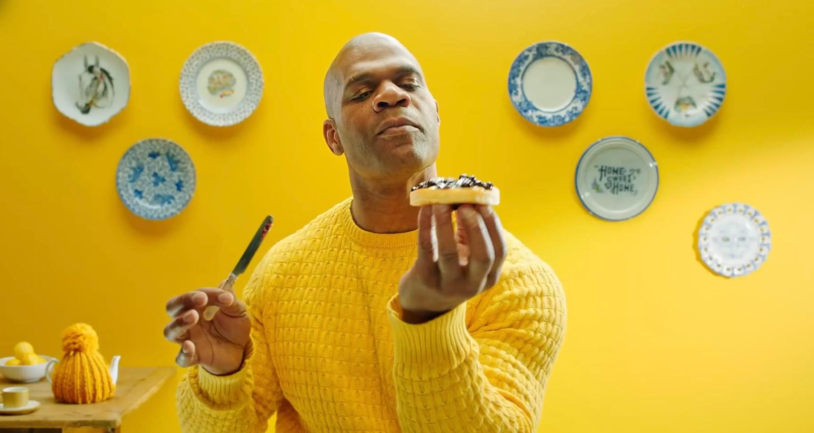 a man in a yellow sweater eating a piece of cake