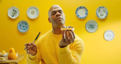 a man in a yellow sweater eating a piece of cake