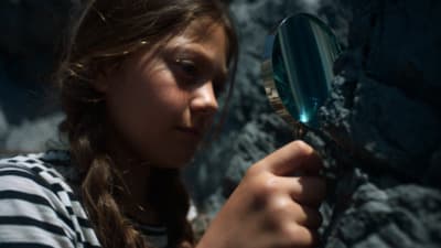 a young girl holding a magnifying glass up to her face