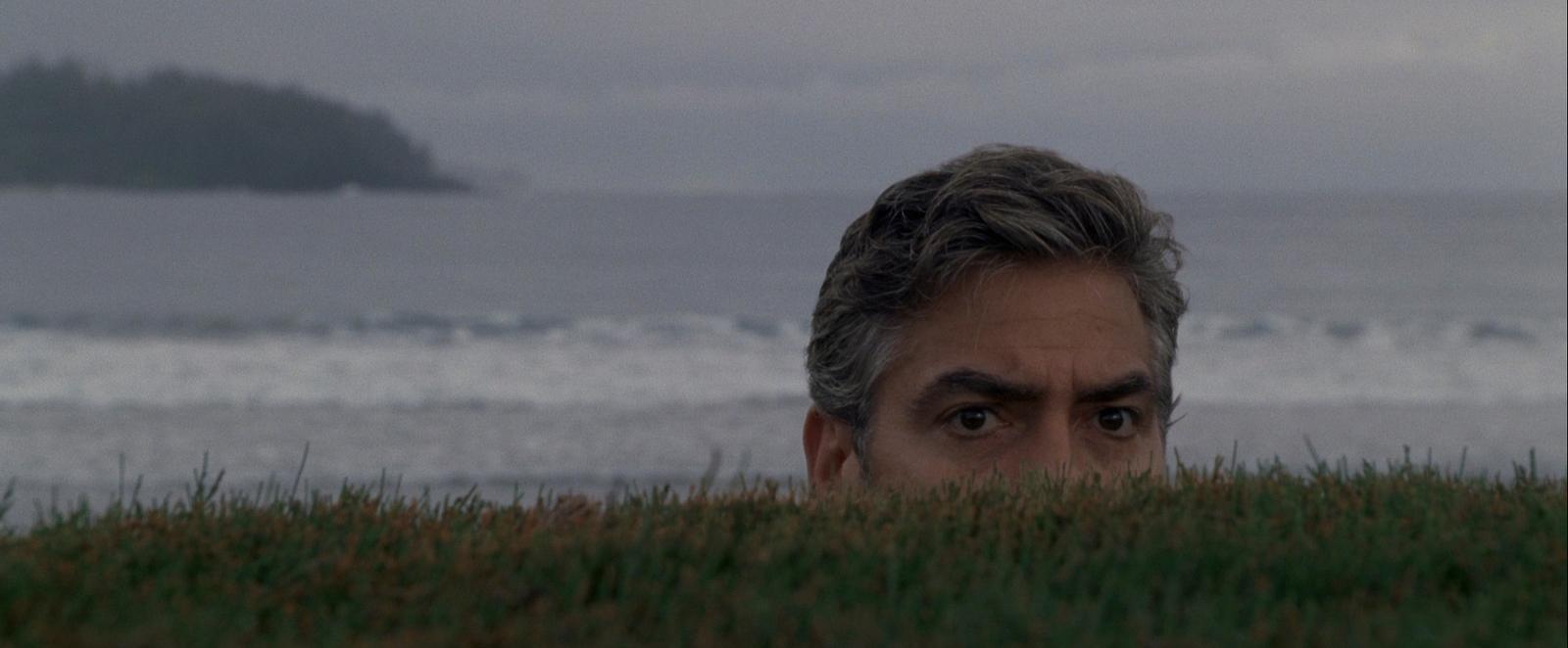 a man hiding in the grass looking at the camera