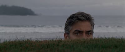 a man hiding in the grass looking at the camera