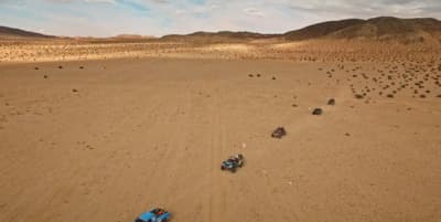 a group of four vehicles driving across a desert