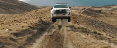 a white truck driving down a dirt road