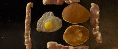 bacon, eggs, and sausages are being cooked on a grill
