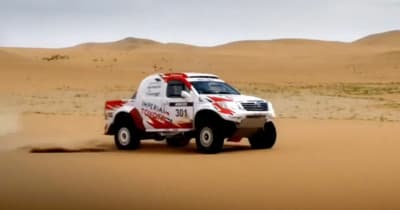 a white truck driving through a sandy desert