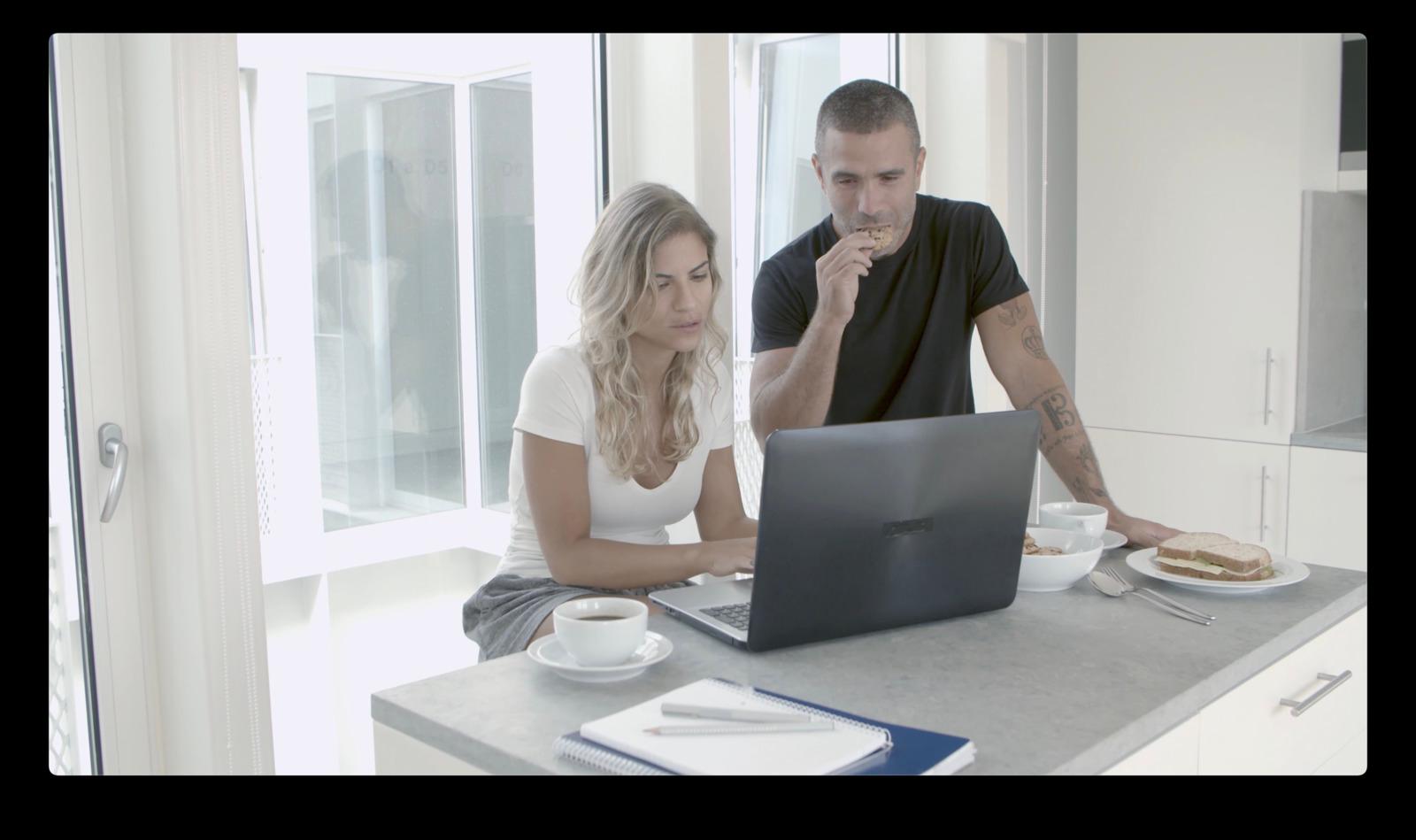 a man and a woman sitting at a table with a laptop