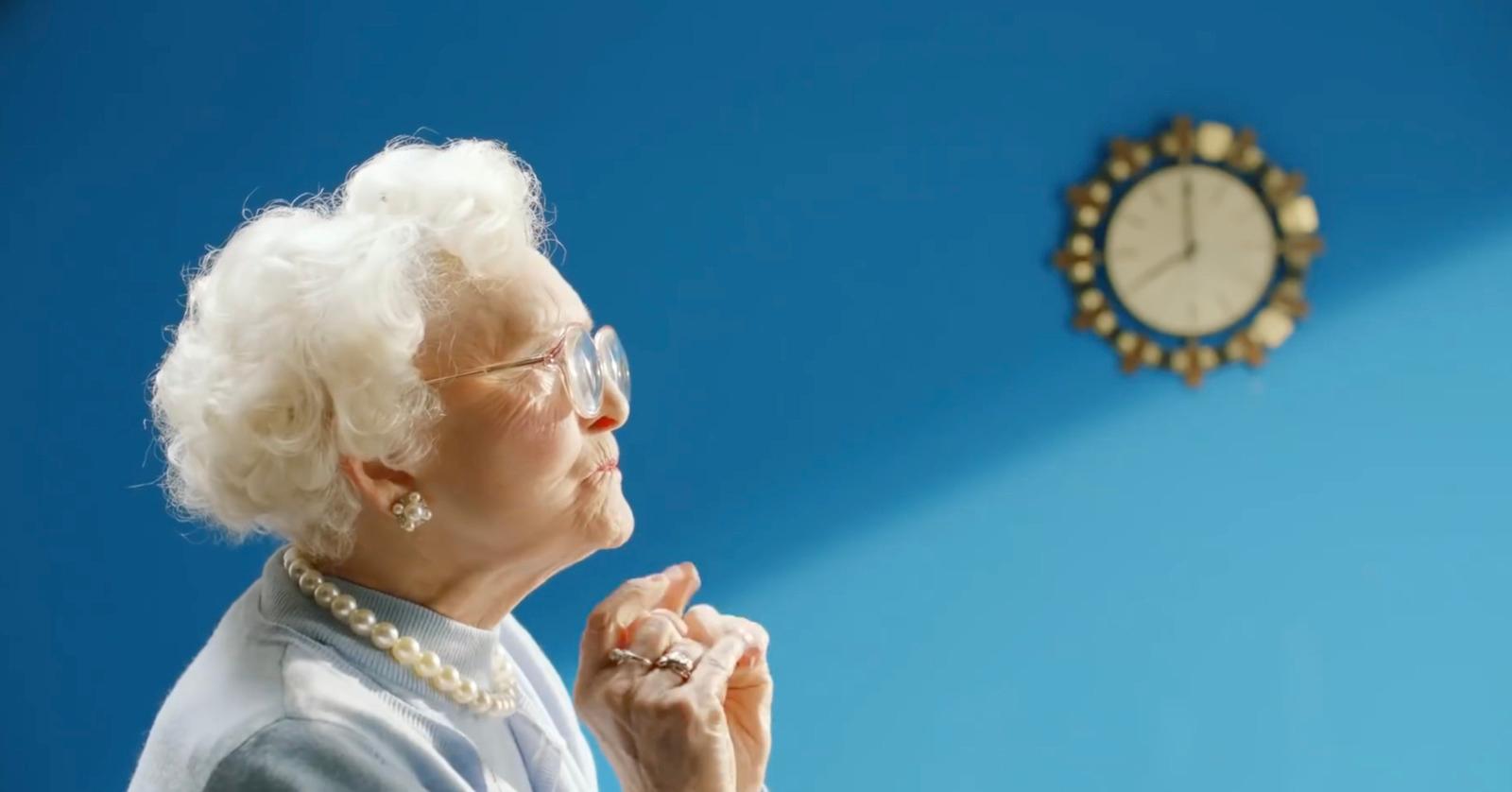 a woman in glasses is looking up at a clock