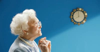 a woman in glasses is looking up at a clock