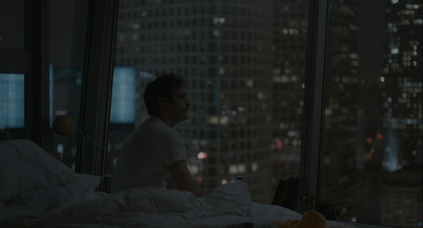a man sitting on a bed looking out a window