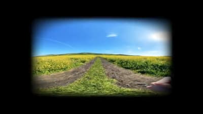 a person holding a camera in front of a field