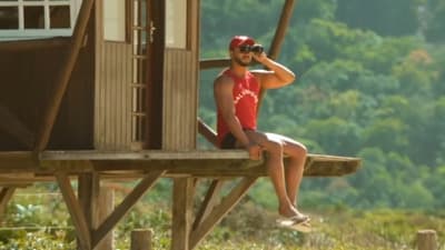 a man in a red shirt sitting on a wooden bench