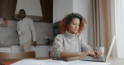 a woman sitting at a table using a laptop computer