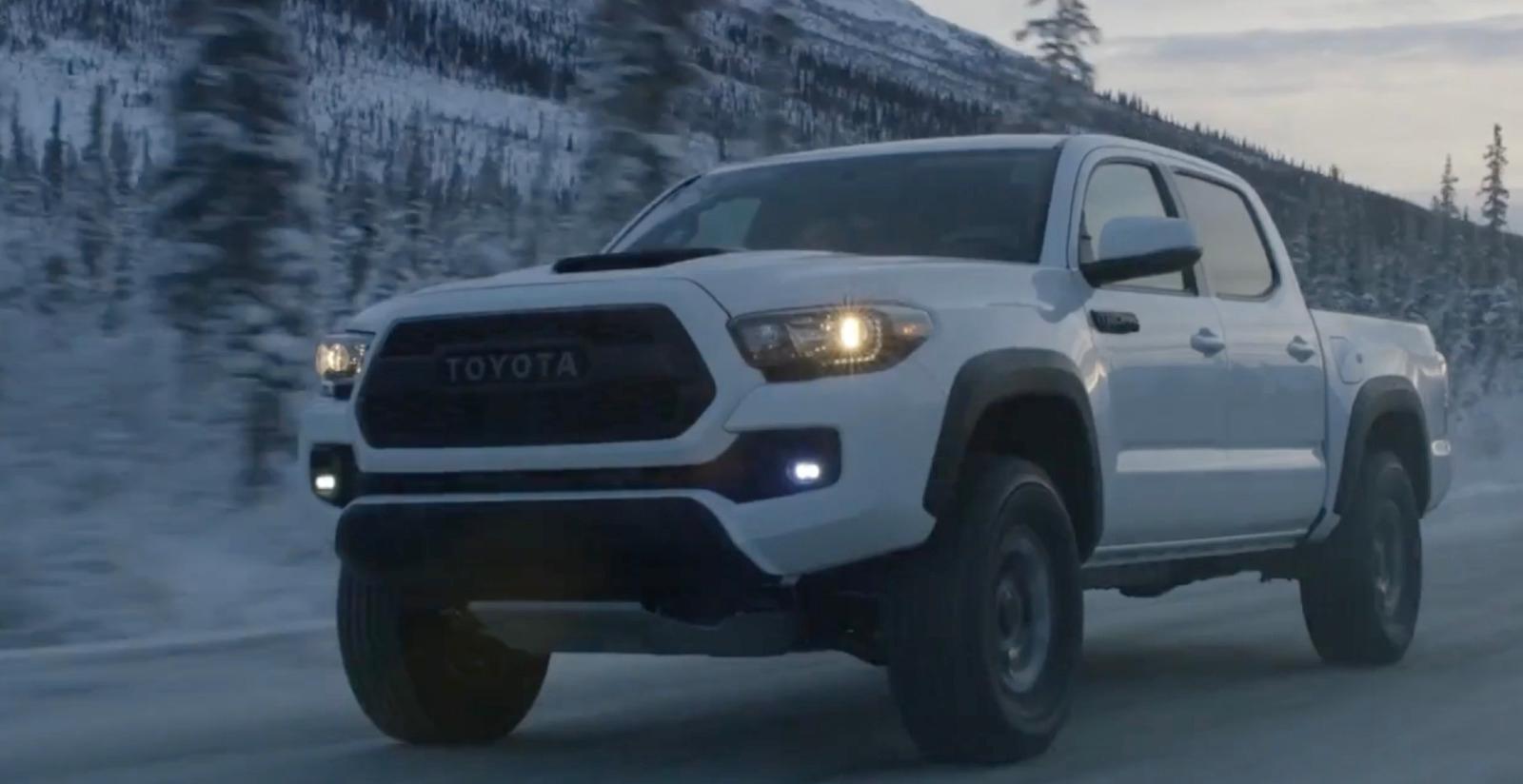 a white toyota truck driving down a snowy road