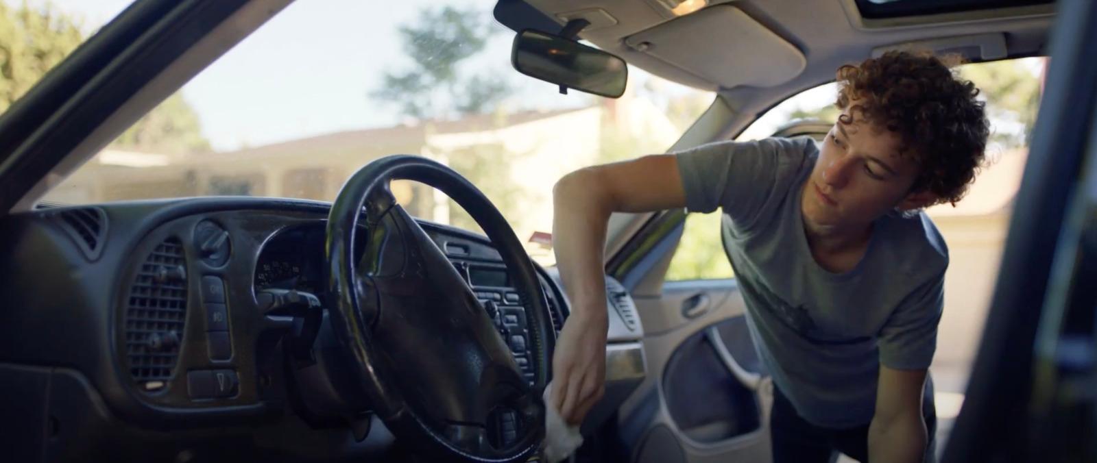 a young man sitting in the driver's seat of a car