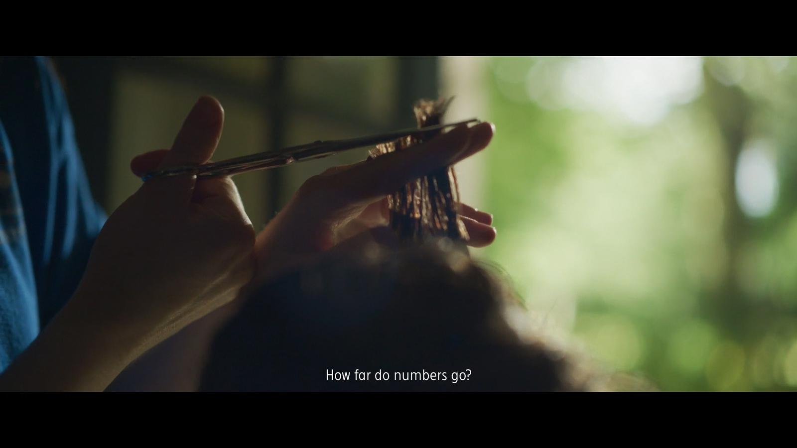 a person cutting another persons hair with scissors