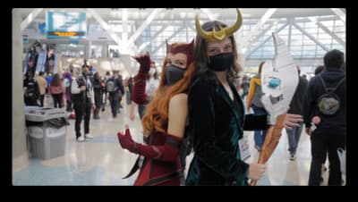 a woman in a costume standing next to a man in a devil mask