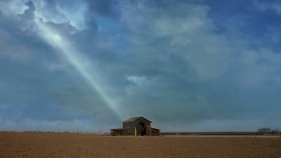 a barn in a field under a cloudy sky