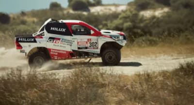 a red and white truck driving down a dirt road