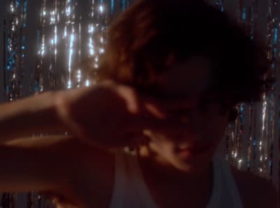 a man in a tank top standing in front of a curtain
